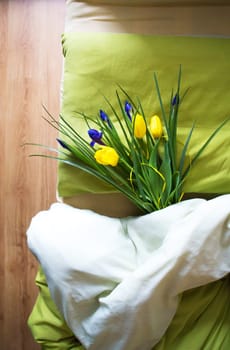 a bouquet of beautiful yellow tulips and irises lie on the bed-morning, surprise.