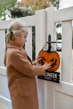 A girl with Carved pumpkin on the fence of the house
