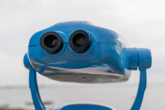 Metal blue stationary outdoor binoculars on the observation deck overlooking the sea. paid binoculars for tourists to view the sights.