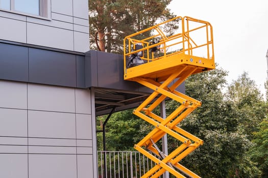 mobile lifting cradle. Construction scissor lift. electric mobile lifting cradle on wheels for work at height. Scissor lift platform with hydraulic system painted in orange colors. close-up