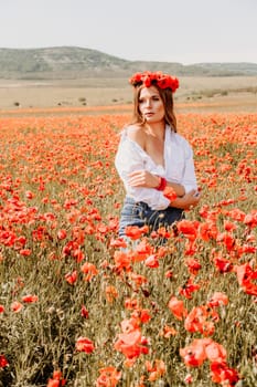 Happy woman in a poppy field in a white shirt and denim skirt with a wreath of poppies on her head posing and enjoying the poppy field