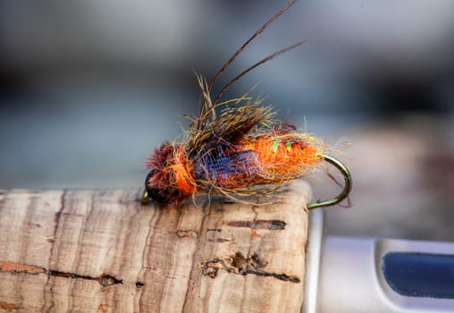 Wet fly nymph fishing pattern at a river in Oregon set on the cork handle of a rod.