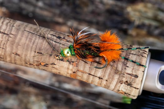 Wet fly nymph fishing pattern at a river in Oregon set on the cork handle of a rod.