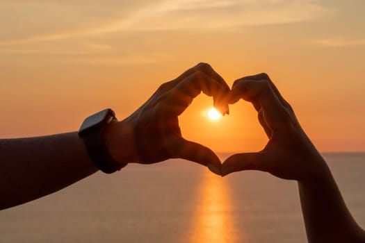 Hands heart sea sanset. Hands forming a heart shape made against the sun sky of a sunrise or sunset on a beach.