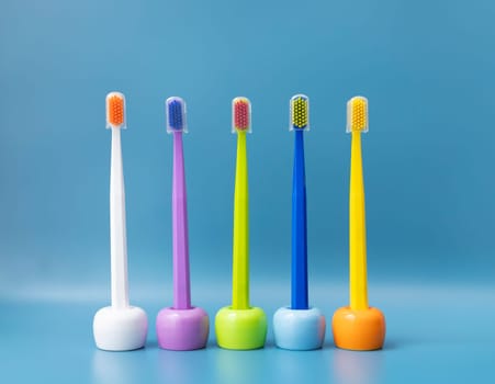 Large Number of Brightly Colored Toothbrushes On Stands, Holder in Row On Blue Background. Morning hygiene, Bathroom accessories. Dental Health Care. Horizontal Plane. High quality photo