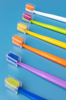 Large Number of Multicolored Toothbrushes in Row On Blue Background. Morning hygiene, Bathroom accessories. Dental Health Care. Vertical Plane. High quality photo