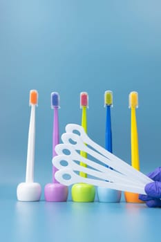 Large Number of Cleaning Tongue Scrapers and Multicolored Toothbrushes On Blue Background. Morning hygiene, Bathroom accessories. Dental Health Care. Vertical Plane. High quality photo