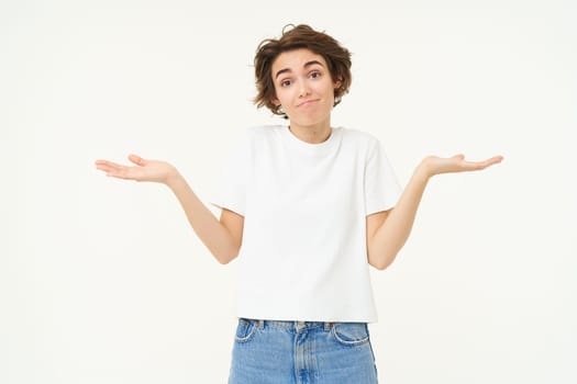 Woman shrugs her shoulders, looks clueless, doesnt know anything, stands confused against white background.