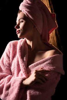 Sexy young girl wearing pink bathrobe and towel on her head shot after shower in the dark