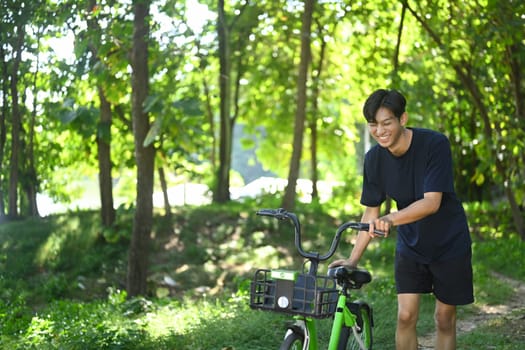 Happy male cyclist riding a bike on forested trail at sunrise.