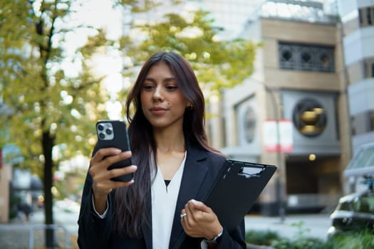 Professional Hispanic businesswoman using mobile phone at the downtown district.