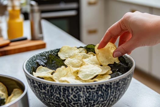 Woman grabbing a delicious cassava chips with nori seaweed in a bowl in a modern kitchen