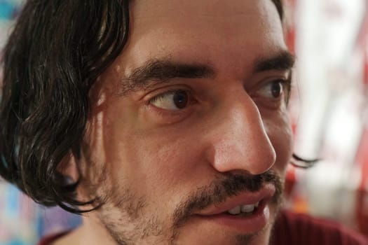 A contemplative moment captured in an artistic environment featuring a man with expressive features and wavy hair at an intimate gathering