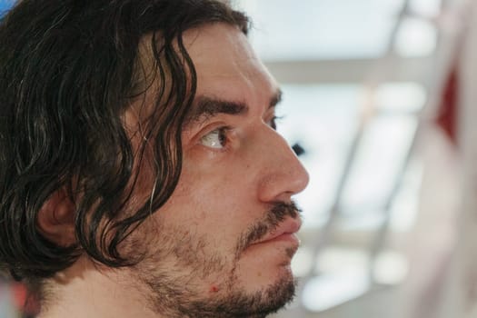 The man gazes with interest, his tousled hair framing a thoughtful face.