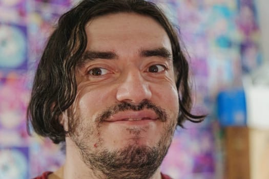 An individual with a friendly expression showcases warmth and enthusiasm, surrounded by colorful artwork