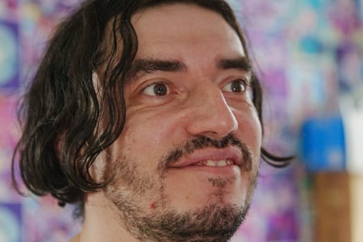 An individual with a friendly expression showcases warmth and enthusiasm, surrounded by colorful artwork