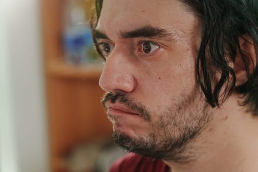 The man gazes with interest, his tousled hair framing a thoughtful face.