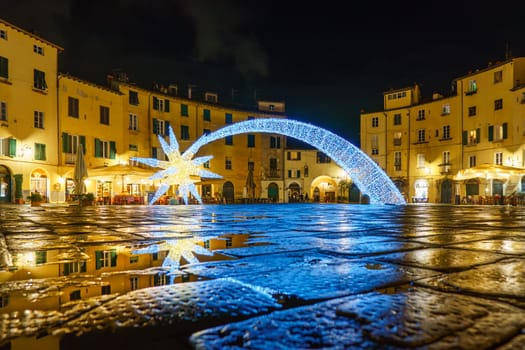 Beautiful view from the ground of the Amphitheatre square in Lucca at night during the Christmas holidays. Italy