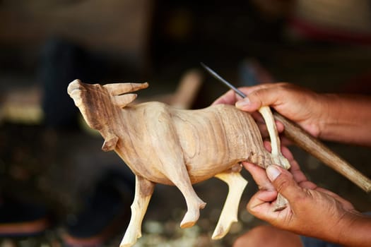 A man makes a wooden sculpture of a bull with his own hands.
