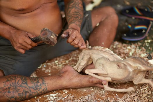 A man makes a wooden sculpture of a bull with his own hands.