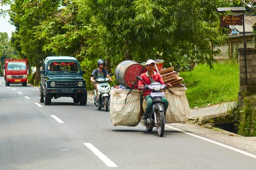 A person on a motorcycle rides a scenic asphalt road in Asia. Bali, Indonesia - 01.03.2018
