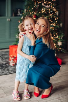 Little girl and her mom on Christmas morning at home. Girl is sad about something and mother is hugging her