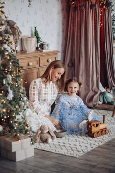 Little girl and her mom on Christmas morning at home. Girl is sad about something and mother is hugging her