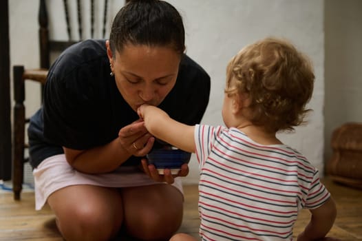 A touching scene of a mother gently holding her child's hand, capturing warmth and connection. The intimate indoor setting enhances the emotional bond shared between them.