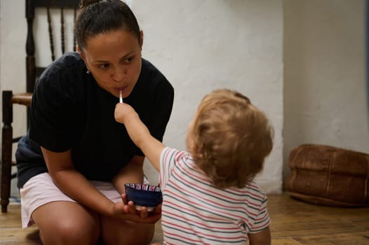 A touching scene of a mother and child sharing a playful moment during feeding time, illustrating warmth and connection in a cozy home setting.