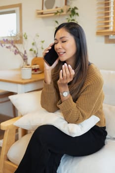 Attractive millennial woman having phone conversation in living room.