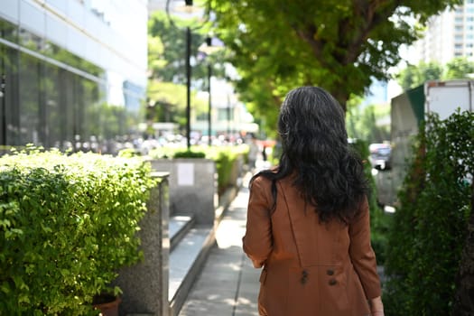 Stylish senior entrepreneur strolling through urban greenery.