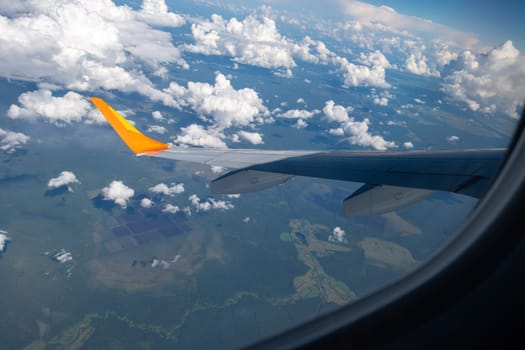 View from airplane window on wing and landscape with clouds on window during flight. Selective focus.