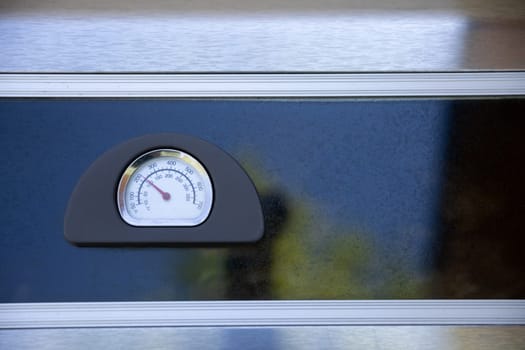 This is a closeup view of a grill thermometer, which prominently displays various temperature readings