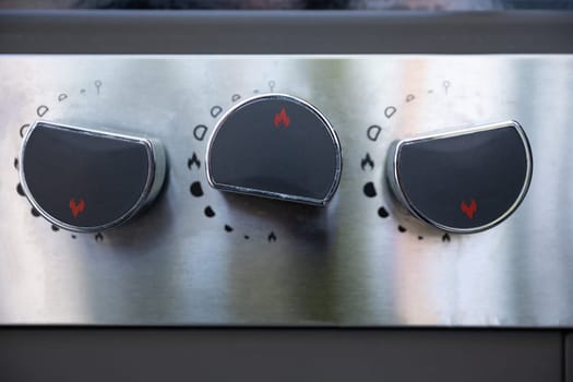 A detailed view featuring black stovetop knobs against a sleek stainless steel background, perfect for culinary media