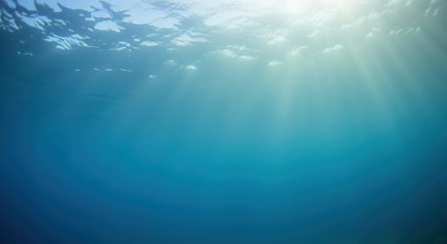 Sunlight filters through ocean waves, casting gentle rays upon the tranquil underwater scene. the serene blue tones create a peaceful ambiance, perfect for marine-themed designs, prints, or digital backgrounds.