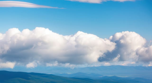 Expansive blue sky and fluffy white clouds drift above serene mountain ranges, creating a tranquil scene ideal for nature-themed designs. the contrast between the sky and the mountainous terrain emphasizes the beauty of untouched landscapes.