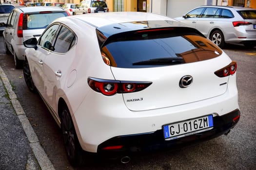 Cremona, Itally - October 6th 2024 White mazda 3 hatchback 2.0 skyactiv-x parked on a city street, highlighting its modern design and sleek features from the rear view