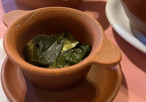 Shot from aboveof clay pot with coca leaves to prepare tea. Typical infusion of Jujuy,Arg.Delicacies of culinary tourism. Healthy and digestive coca tea.