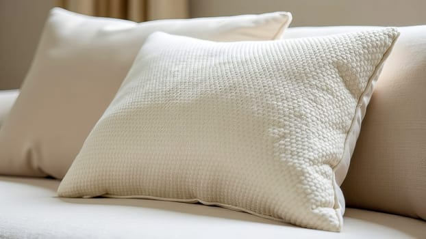 A close-up of a sofa cushion made of textured light boucle fabric, against a background of other simple light pillows. AI generated.