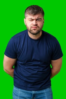 Man expressing confusion with crossed arms in front of a bright green background during a casual moment