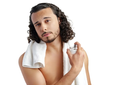 A young man with curly hair applying fragrance after a shower while smiling at the camera close up