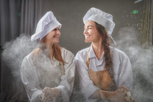 Two friends enjoy a playful moment in the kitchen, surrounded by flour, showcasing their love for cooking and friendship.