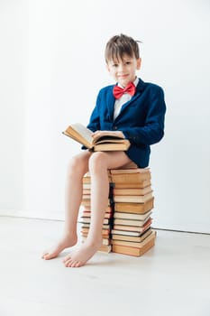 Boy in business suit without pants sitting on books
