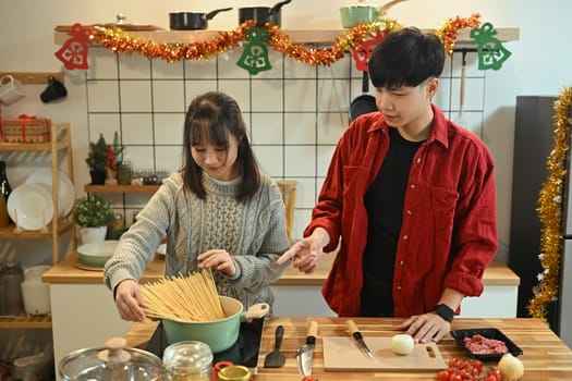 Attractive young couple enjoying dinner preparations in kitchen on Christmas eve.