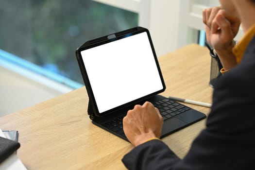 Focused male entrepreneur using digital tablet on wooden working desk.