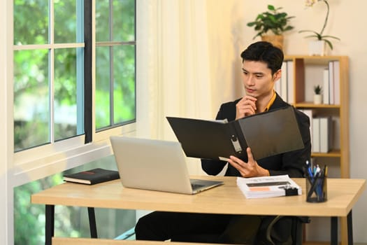 Handsome male account manager checking reports at his office desk.