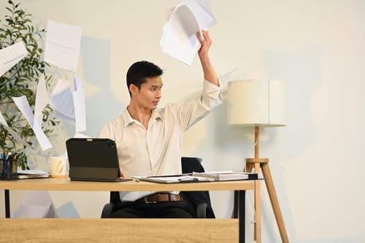 Frustrated office worker throwing documents in anger. Stress at work concept.