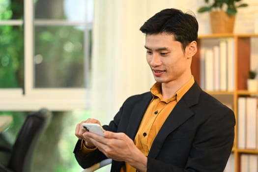 Professional businessman in a suit using his smartphone in modern office.