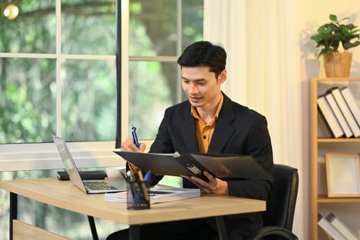 Professional businessman checking reports at his modern workplace.