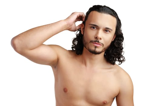 Young man with curly hair thoughtfully posing against a plain background in a studio setting